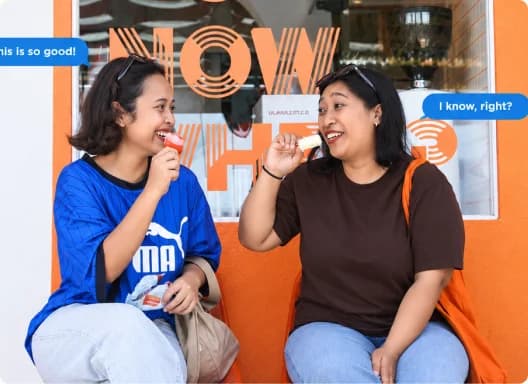 Two friends sharing delicious gelato sticks outside a café